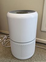 Front and side view of Levoit air purifier showing cylindrical body and perforated intake