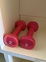 Two red vinyl-coated dumbbells showing weight marking