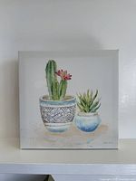 Front view of square canvas showing potted cactus and succulent image, artist signature visible
