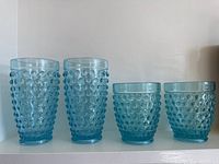Four blue hobnail glass tumblers, two heights, displayed side by side
