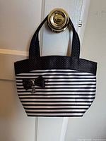 Front view of striped tote showing bow, charm, handles, and overall condition