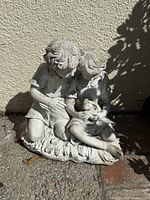 Front view of cast stone boy and girl statue