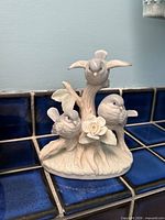 Front view of ceramic sculpture showing three birds on tree and white rose