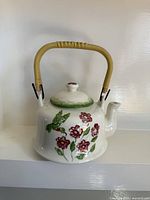 front view of ceramic teapot showing floral and hummingbird design with handle