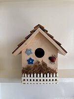 Front view showing entrance hole, flower appliques, ladybug, moss and picket fence