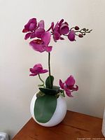 Full view of faux orchid in white round vase