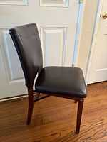 Front angled view showing vinyl seat/back and wood legs