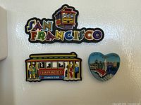 All three San Francisco souvenir magnets on a refrigerator door