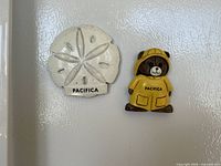 Front view showing both Pacifica souvenir magnets on fridge door