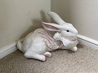 Full view of reclining ceramic bunny showing ribbon motif