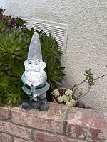 Full view of painted vintage gnome statue on brick ledge