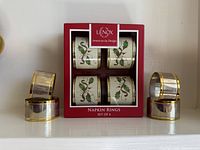Boxed set of four Lenox porcelain holly napkin rings with additional four metal rings displayed