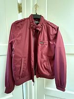 Front view of burgundy Members Only jacket on hanger
