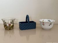 Front view of three items: glass floral cup, blue ceramic basket, white porcelain bowl