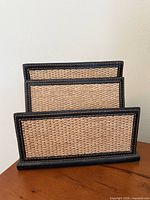 angled view showing three ascending straw panels within black leather frames on a leather base