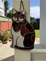 Front view of pottery calico cat wall plaque hanging outdoors