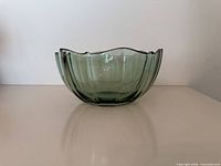 Side view of green glass bowl showing scalloped rim and faceted sides