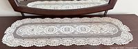 Full view of white lace table runner on dark surface