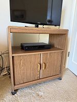 Full view of woodgrain cabinet with TV and electronics on and in stand