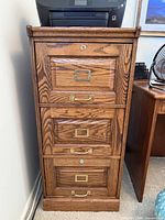 Front view of oak file cabinet showing all drawers and hardware