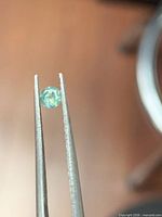 Close-up of single 3 mm alexandrite held in tweezers