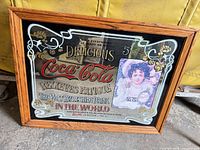 Front view showing Coca-Cola advertisement print on mirror and oak frame