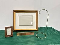Group shot showing all four items: large gold frame, small brown frame, brass nameplate, brass display stand