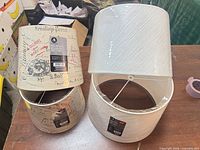 Two beige printed and two white crinkle-paper Hometrends lamp shades, tags visible