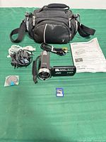 All items laid out: camcorder, cables, lens cap, SD card, manual, carrying case