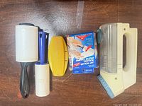 Group view of Windmere shaver, two lint rollers, yellow brush, refill box