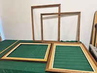 Four wood frames standing and lying on table showing finishes and sizes