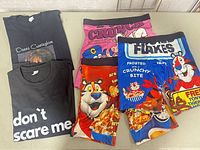 All five items laid out: two black T-shirts and three graphic boxer shorts