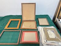 Seven wooden frames and packaged mats laid out on green surface