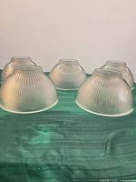 Five matching frosted ribbed glass light shades grouped together showing exterior texture