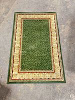 Full view of rectangular green and cream bordered rug