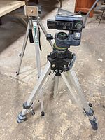 Front view showing Slik tripod with head details and Velbon tripod in background