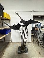 Full view of tall wrought iron sculpture with two birds and reed-like rods