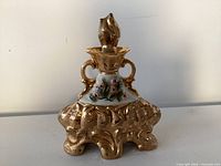 Front view showing gold finish, floral panel and stopper