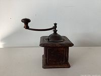 front view of square wooden coffee grinder with crank