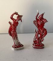 Both red glazed ceramic dancer figurines side by side