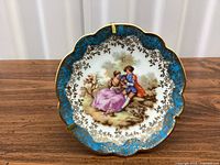 Front of saucer showing pastoral scene, turquoise and gilt border