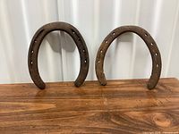 front view of both horseshoes standing upright on wood surface