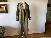 Full front view of long olive trench coat on mannequin