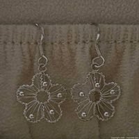 Full view of both daisy filigree earrings hanging from French hooks