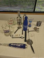 Group shot of bar tools, tap handle, branded glasses and accessories
