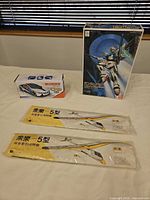 Overall lot showing two glider wings, Gundam F91 model kit box, boxed toy car