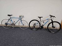 Both bicycles side by side on floor against wall