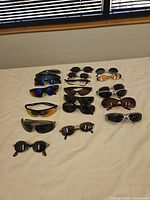 Fifteen sunglasses laid on bed showing full lot