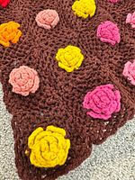 close-up of brown crochet with yellow, pink, orange rose appliqués