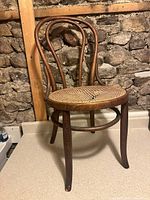 Full view of bentwood chair against stone wall